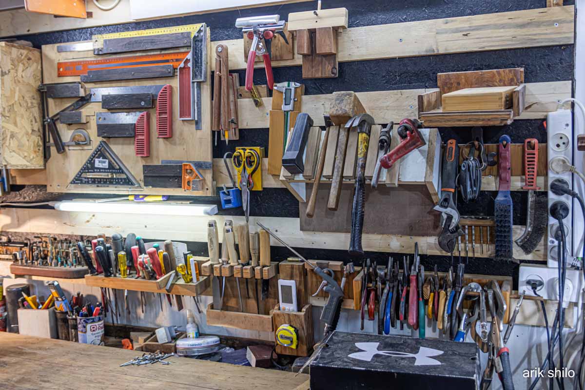 מבט נוסף על קיר עמוס מכלים אבל מסודר בפטנטים בנגריה של שי קורן