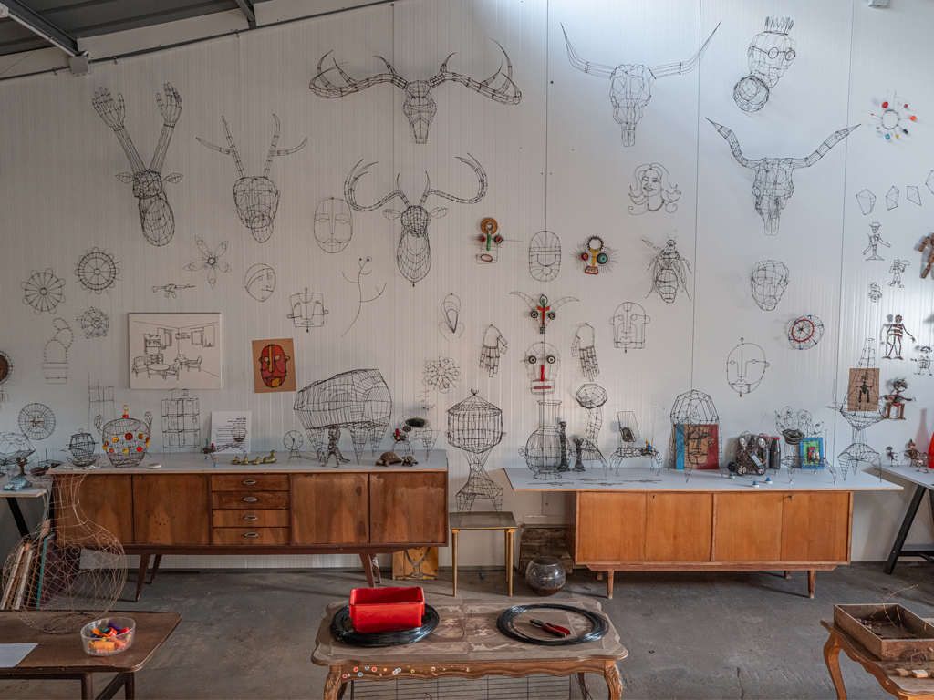 תמונה של קיר אחר בסטודיו של קובי סיבוני, הוא גבוה מאוד ולפניו שעונות שידות. קוב היצירות בתמונה זו הן תלת מימדיות ומזכירות ראשי חיות כפי שציידים תולים את הראשים לתצוגה. חלק נראות כמו רובוטים, כלובים ודימויים מופשטים. ישנן גם מגוון של יצירות דו-מימדיות.