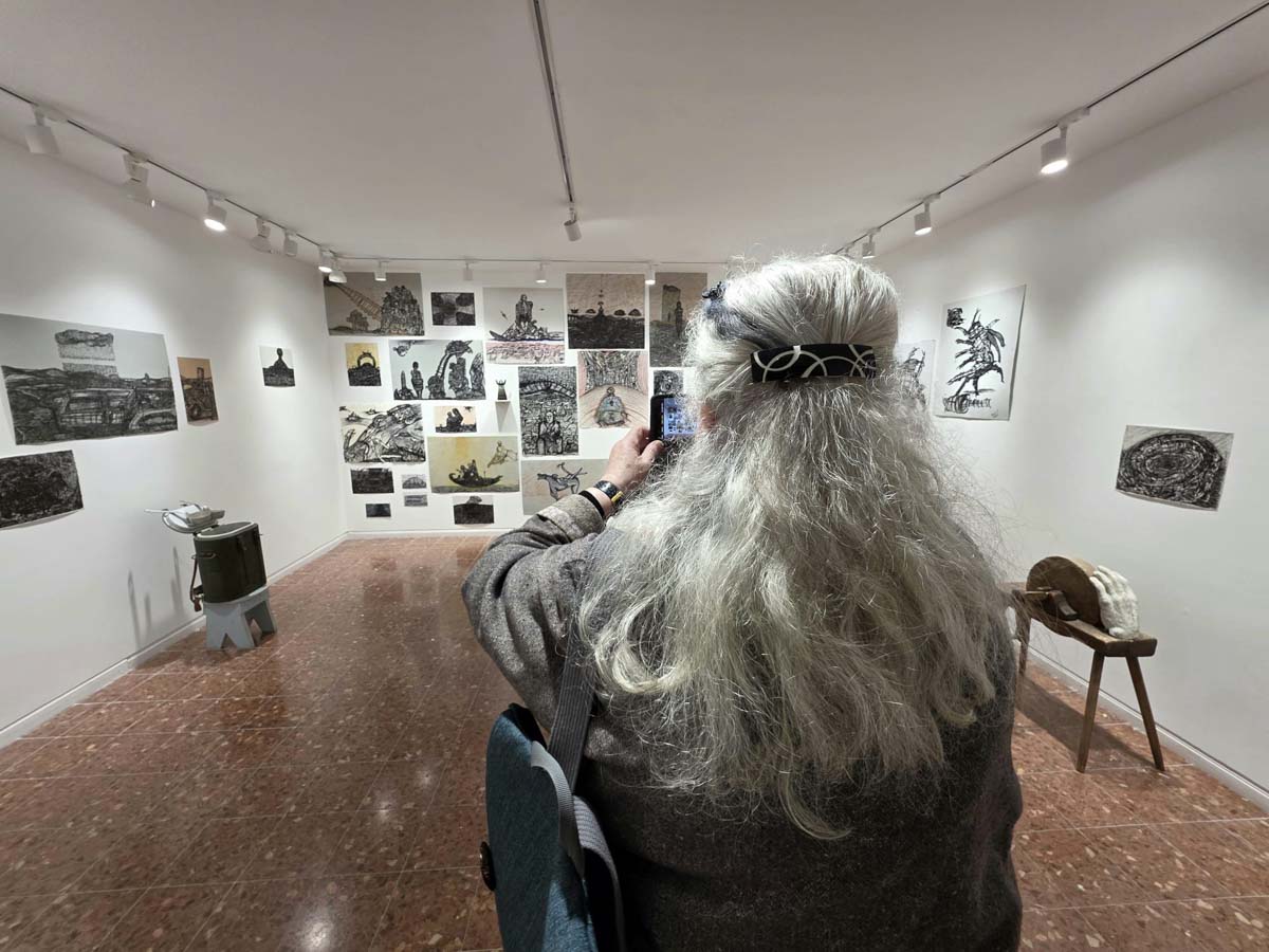 אישה מצלמת את התערוכה בחלל הגלריה.